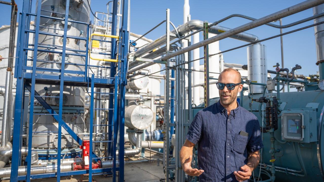 Man stands among pipes and tanks